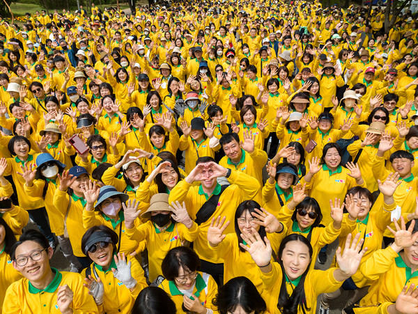 WeLoveU members, wearing yellow T-shirts, wave their hands and make a heart. More than 7,000 people attended the walkathon, which was held for the first time in three years after it could not be held due to the pandemic.