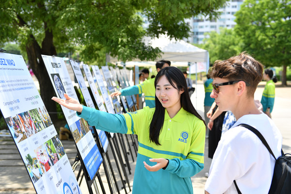 여의도한강공원에서 펼쳐진 거리캠페인에 참여한 외국인이 패널 내용을 경청하고 있다. (사진제공=하나님의교회)