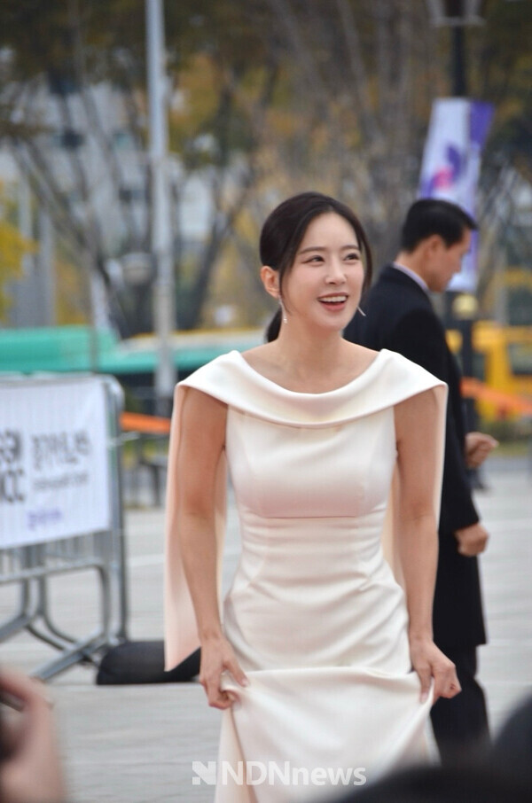 화려한 화이트 골드드레스로 레드카펫을 걷고 있는 배우 송민경, 기자들과 팬들에게 웃음으로 마음을 전하고 있다 / 사진촬영 = 김하원 기자