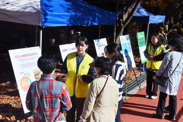 경기 동두천시 소요산에서 열린 하나님의 교회 ‘희망의 숲’ 캠페인에서 봉사자들이 사막화의 심각성과 해법을 담은 패널 전시를 하는 모습. 동두천을 찾은 시민들이 봉사자들의 설명을 유심히 듣고 있다. (사진제공=하나님의교회)