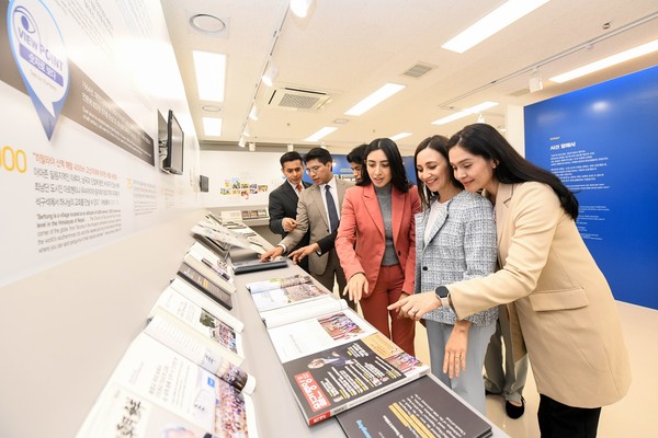 81차 해외성도방문단이 'Media's Views' 전시에서 도슨트의 설명을 들은 후 언론자료를 둘러보며 서로 이야기를 나누고 있다. (사진제공=하나님의교회)