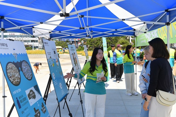 부산 광안리해수욕장에서 25일 ASEZ WAO가 개최한 거리캠페인에서 시민들이 패널 전시를 통해 플라스틱 오염의 심각성을 확인하고 있다. (사진제공=하나님의교회)